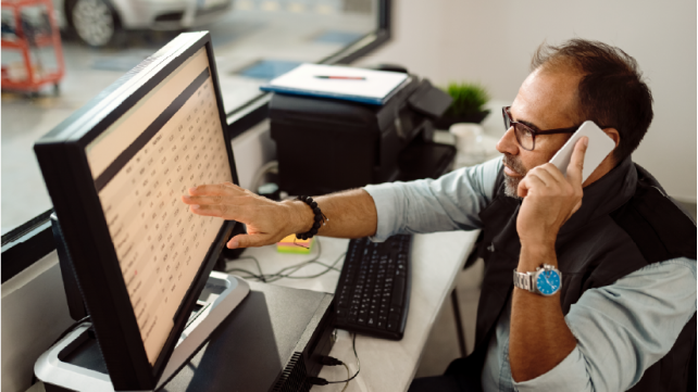 Man working at a computer and talking on the phone