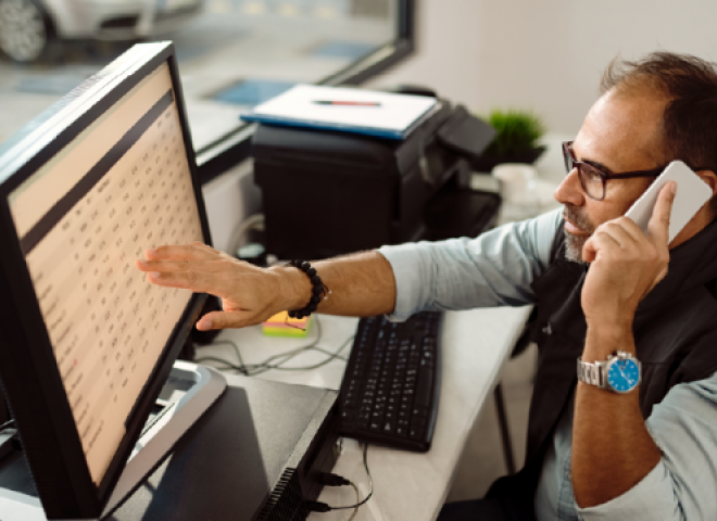 Man working at a computer and talking on the phone